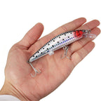 Fishing lure held in a hand against a white background