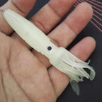 White squid lure held in a hand against a dark background