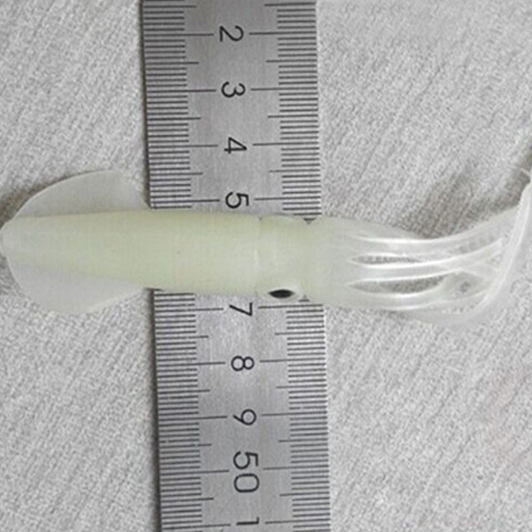Clear plastic tube with a white string-like material, measured against a ruler on a textured gray background.