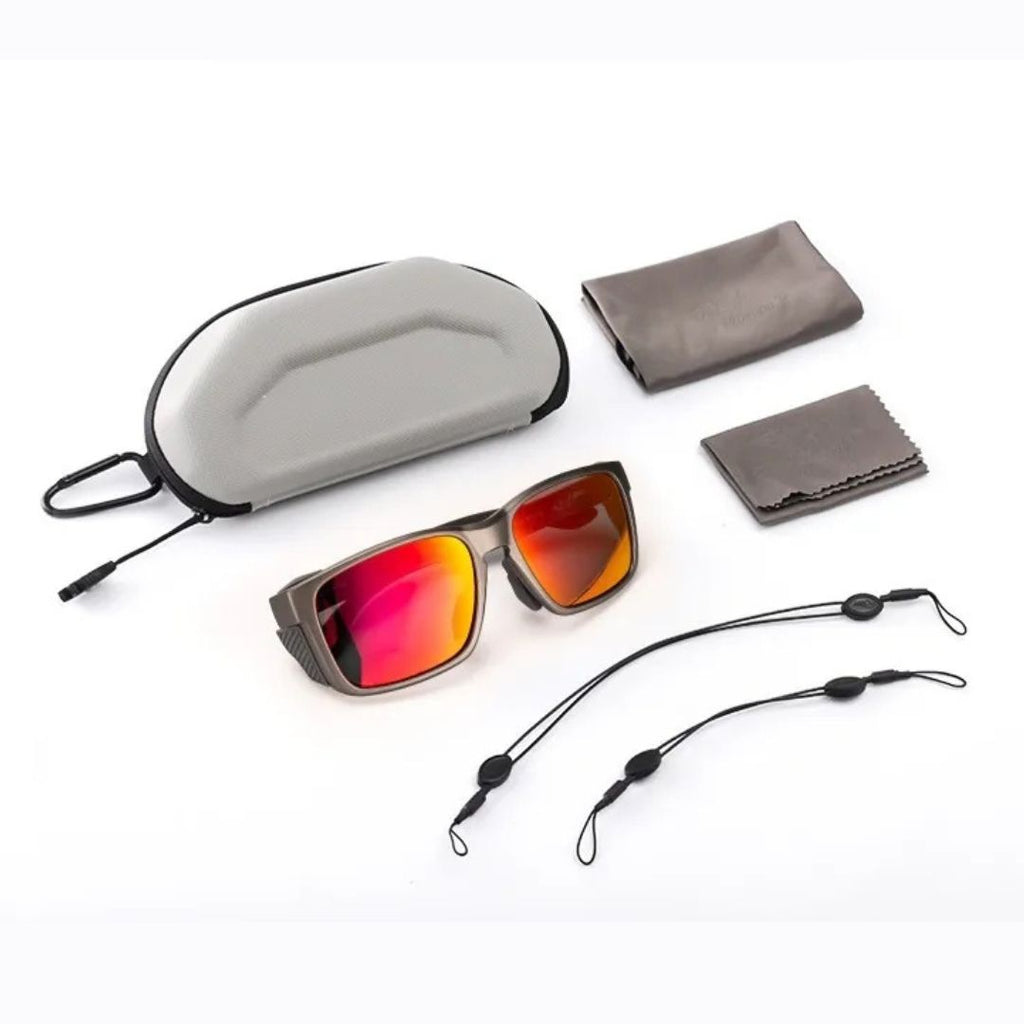 Full sunglasses kit displayed on white background, including mirrored polarized sunglasses, a hard-shell carrying case, soft pouch, microfiber cleaning cloth, and two adjustable retention straps. Ideal for outdoor use and travel.