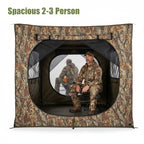 Interior view of the NEXTBAIT VS270 hunting blind, showing a hunter seated comfortably with a bow, demonstrating spacious room for 2-3 people and gear. Reflective window shows exterior view.